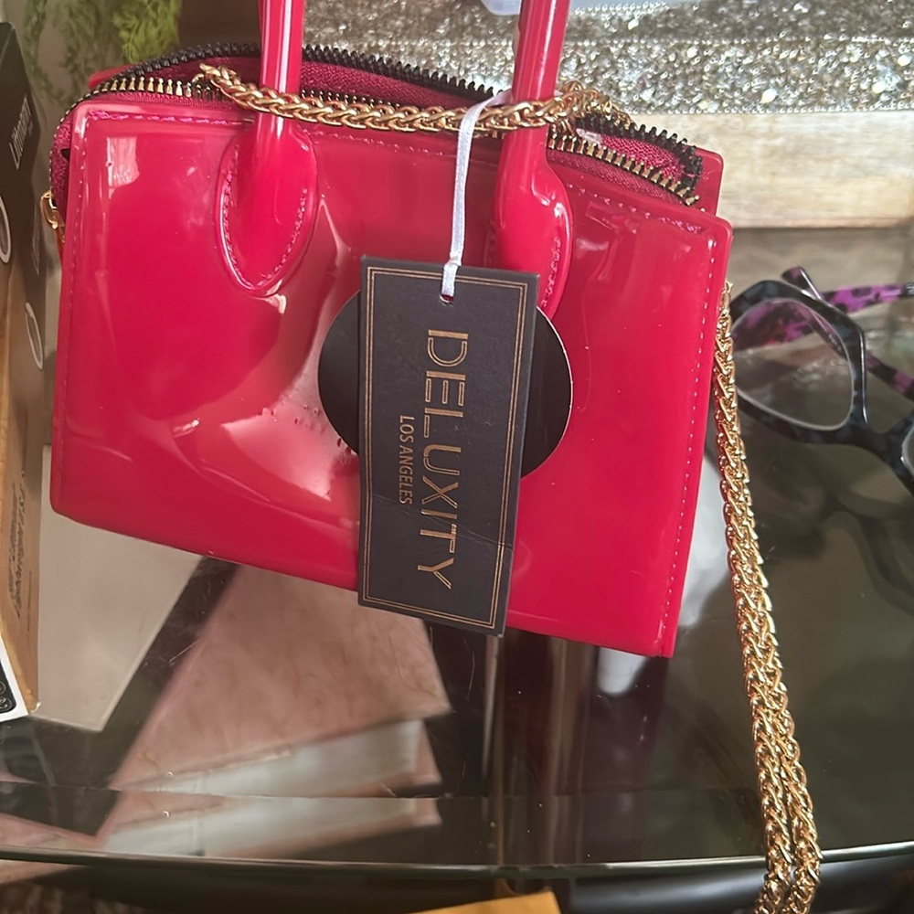 Mini pink cross over bag that has a gold change